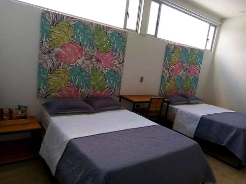 1 dormitorio con 2 camas y un mural en la pared en Hotel La Aldea del Oriente, en Marinilla