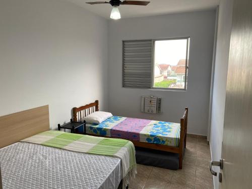 a bedroom with two beds and a window at Apto Guarujá - Asturias in Guarujá