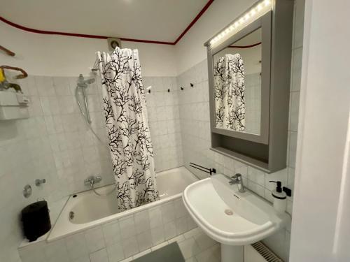 ein Badezimmer mit einem Waschbecken, einer Badewanne, einem WC und einem Spiegel in der Unterkunft Purple Kitchen - Apartment mit großer Wohnküche in Bremerhaven