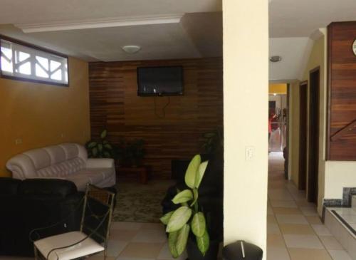 een woonkamer met een bank en een tv aan de muur bij Hotel Morada de Leste in Pontal do Paraná