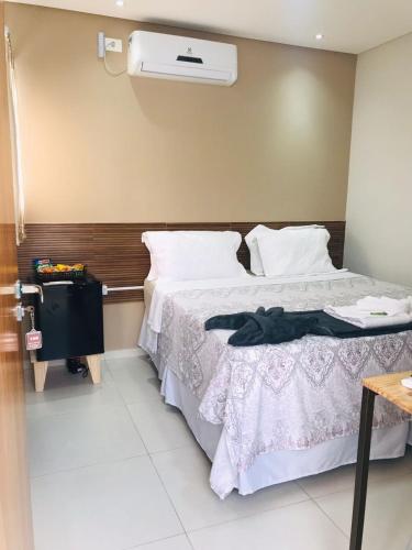 a bedroom with a bed with white sheets and a fan at Hotel Encanto do Sertão in Triunfo