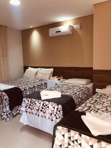 a hotel room with three beds and a air conditioner at Hotel Encanto do Sertão in Triunfo