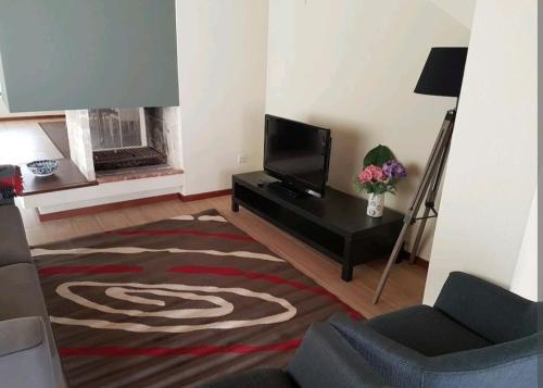 a living room with a television and a fireplace at Vivenda junto ao mar in Mindelo
