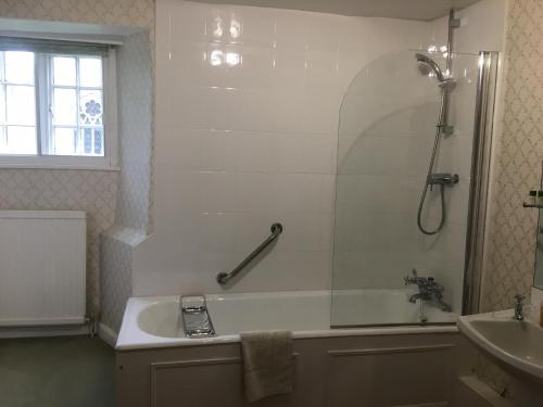 a bathroom with a tub and a shower and a sink at Teigh Old Rectory in Oakham