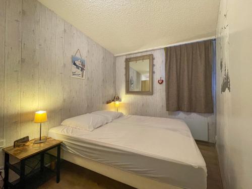 1 dormitorio con 1 cama blanca grande y mesa auxiliar en Alpes Sweet Home - Résidence aux Bergers 5, en L'Alpe-d'Huez