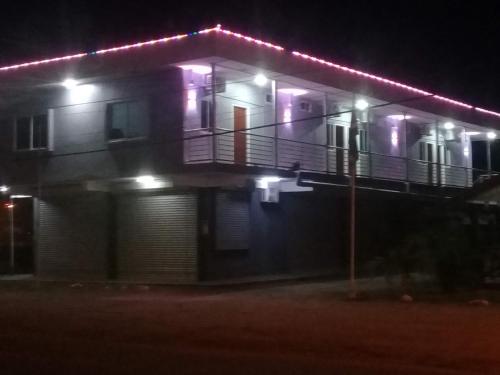 a house with a balcony at night with lights at Douglas Airport Guesthouse in Zanderij