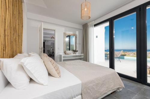 a white bedroom with a bed and a balcony at Hillside Villa - Thea in Limenas