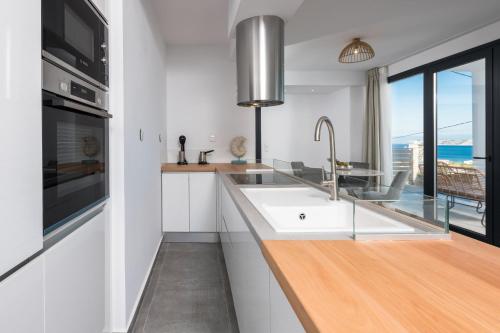 a white kitchen with a sink and a window at Hillside Villa - Thea in Limenas