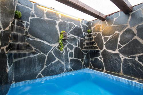 a swimming pool with a stone wall and a swimming pool at El Eden de Javier in Robledillo