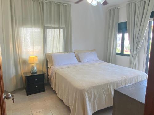 a bedroom with a bed with white sheets and a lamp at Stanza Mare Beach Front in Punta Cana