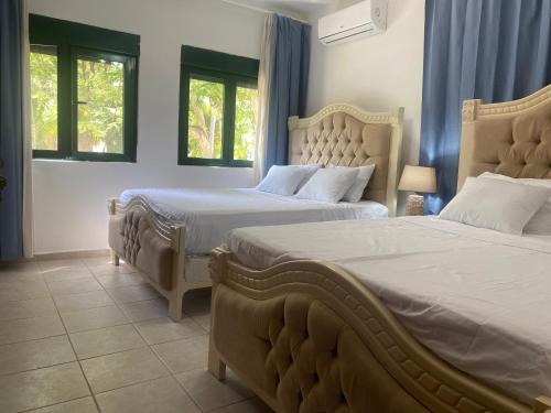 a bedroom with two beds and two windows at Stanza Mare Beach Front in Punta Cana