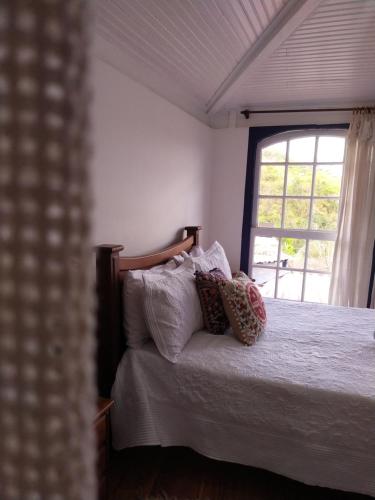 a bedroom with a bed with pillows and a window at É Hostel in Ouro Preto