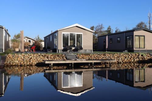 a house with a stone wall next to a body of water at Chalet Earnewald in Earnewâld