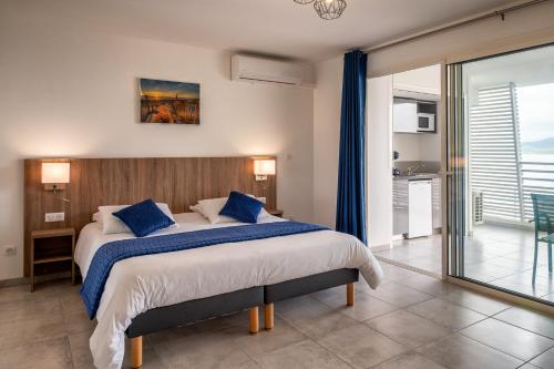 1 dormitorio con 1 cama grande con almohadas azules en Résidence Hôtelière Poséidon Caraïbes en Fort-de-France