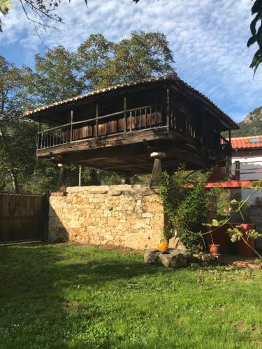 a house with a balcony on a stone wall at Casa rural en Asturias a orillas del río Narcea puerta de Somiedo in Bárzana