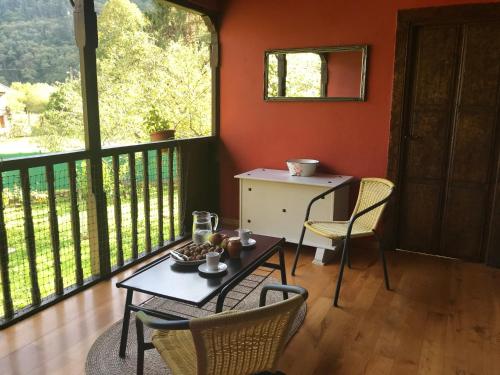 een kamer met een tafel en stoelen op een balkon bij Casa rural en Asturias a orillas del río Narcea puerta de Somiedo in Bárzana