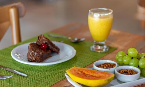 アライアル・ダジュダにあるPousada Casa Cajáの食べ物の皿とオレンジジュースのグラスが置かれたテーブル