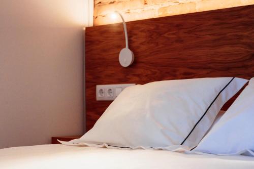 a bed with a wooden headboard and a white pillow at Apartamentos Plaza de España 6 in Villanueva de la Serena