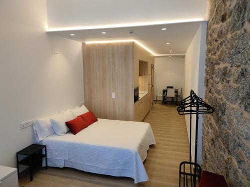 a bedroom with a white bed and a kitchen at Apartamentos A pousa do Asma in Chantada
