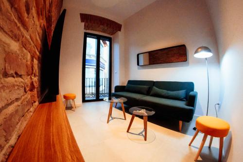 a living room with a green couch and tables at Apartamentos Plaza de España 6 in Villanueva de la Serena