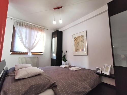 1 dormitorio con 1 cama con 2 almohadas y ventana en Apartament 33, en Cracovia