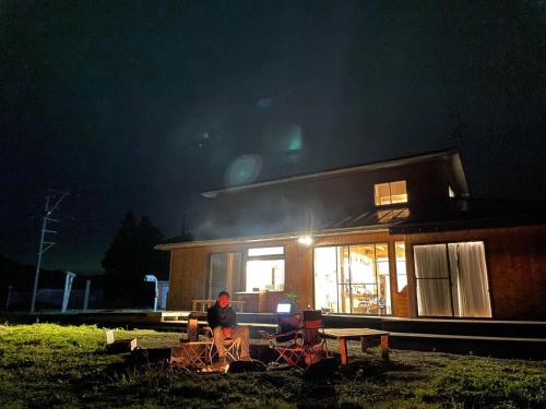 a man sitting in front of a house at night at Guest House Inawashiro~Hanbog~ in Inawashiro