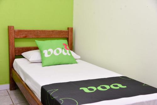 a small bedroom with a bed with a green and white bedspread at VOA Pousada Dos Jasmins in Serra