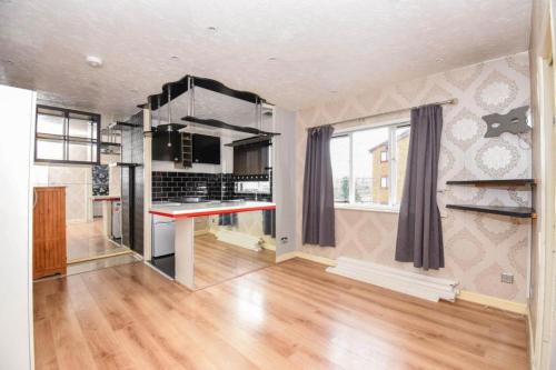 an empty kitchen with a red counter in a room at Peggys Apartment in Hither Green