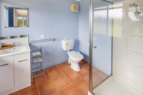 a bathroom with a toilet and a glass shower at Arukah House in Lakes Entrance