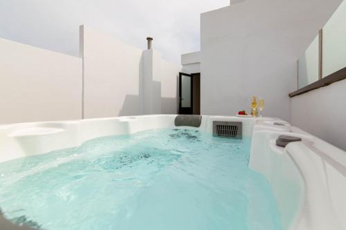 a bath tub with blue water in a white bathroom at Luxury Penthouse With Jacuzzi La Strada in Las Palmas de Gran Canaria