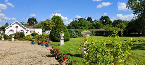 a garden with flowers and vases in front of a house at CHATEAU DE BRINVILLE in Saint-Sauveur-sur-École