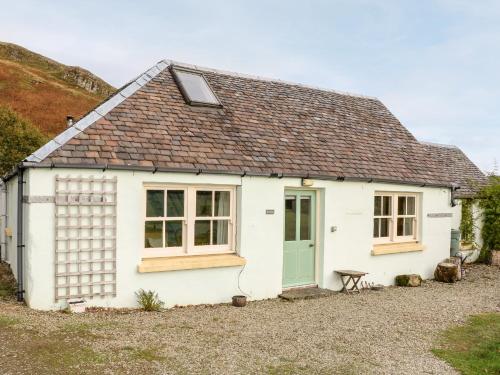 a white cottage with a green door and windows at Mullach in Lunga