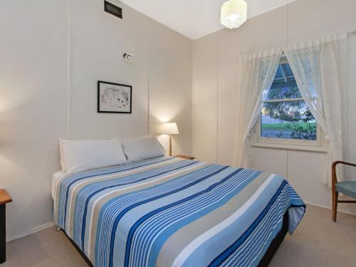 a white bedroom with a bed and a window at Plovers Rest in Port Fairy