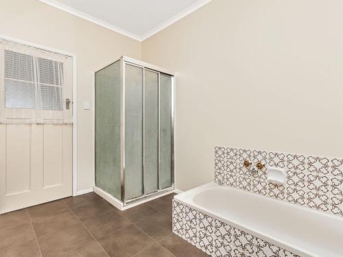 a white bathroom with a tub and a window at Kepal House in Port Fairy