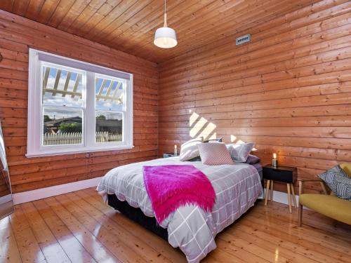 a bedroom with a bed and a wooden wall at Avery Cottage in Port Fairy