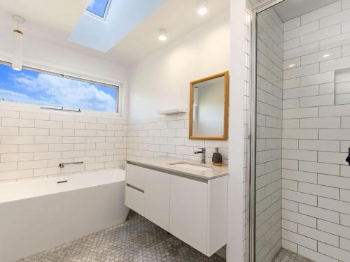 Un baño con bañera, lavabo y espejo. en East Beach Retreat, en Port Fairy