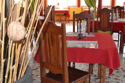 a table with a red table cloth on a table with chairs at Hotel La Marmotte in Matoury