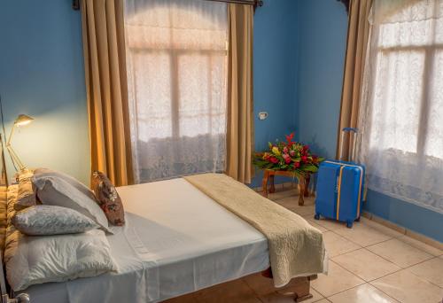 1 dormitorio con cama y pared azul en Tico House Bed & Breakfast, en Cariari