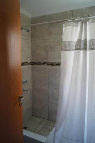 a shower with a white shower curtain in a bathroom at Complejo Los Plumerillos in Chascomús