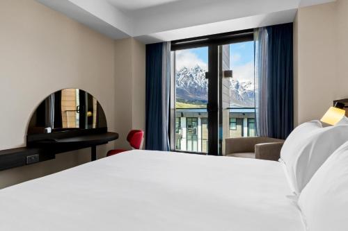 a hotel room with a bed and a large window at Holiday Inn Queenstown Remarkables Park in Queenstown