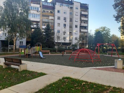 a playground in a park with a large building at Serbian home, Gandijeva 162 in Belgrade