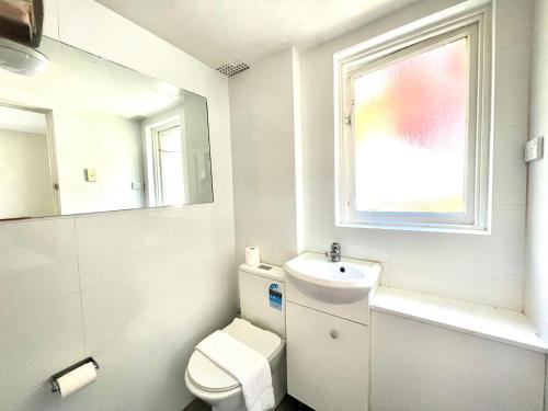 a bathroom with a toilet and a sink and a window at Lotus Stay Manly - Apartment 31B in Sydney