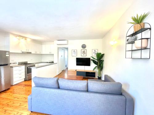 a living room with a blue couch and a kitchen at Lotus Stay Manly - Apartment 31B in Sydney