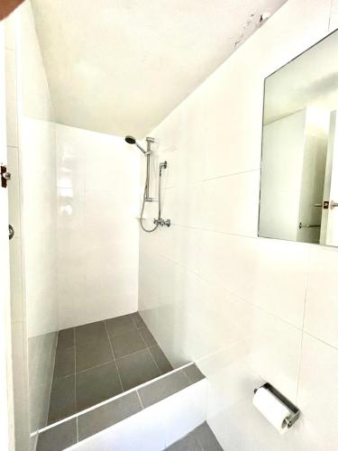 a white bathroom with a shower and a mirror at Lotus Stay Manly - Apartment 31B in Sydney