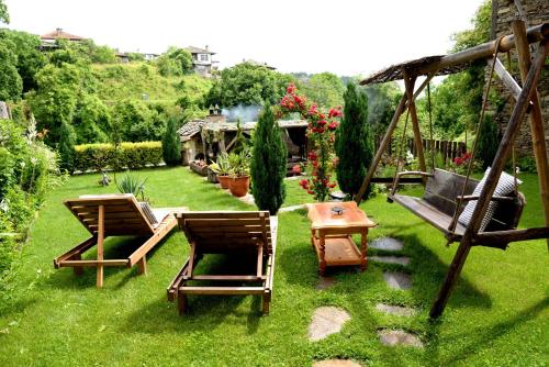 um quintal com duas cadeiras, uma mesa e um baloiço em Guest House Pri Malkiya em Leshten