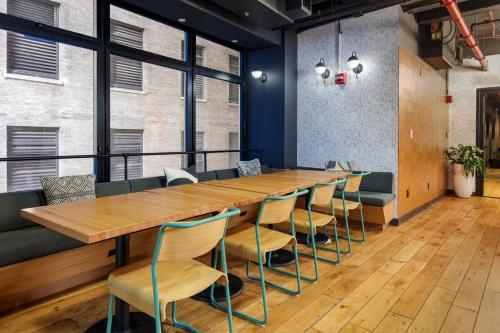 a long wooden table and chairs in a room with windows at Placemakr Wall Street in New York