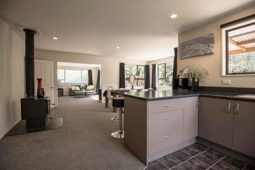 a kitchen with a counter and a living room at Six Kamahi Guest House & Studio Unit in Franz Josef