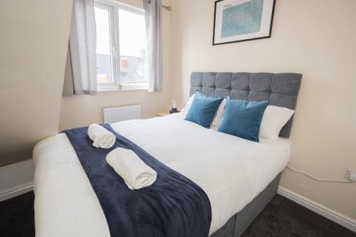 een slaapkamer met een groot wit bed met blauwe kussens bij Luke Stays - Finsbury Street in Monkwearmouth