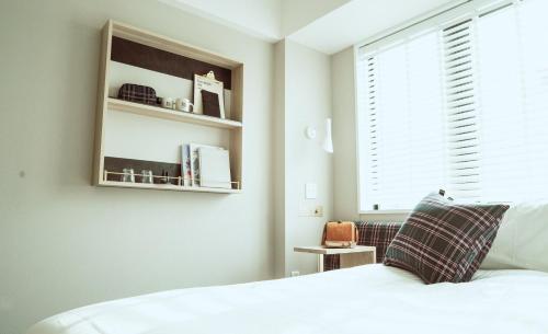 a bedroom with a white bed and a window at Hotel It Osaka Shinmachi in Osaka