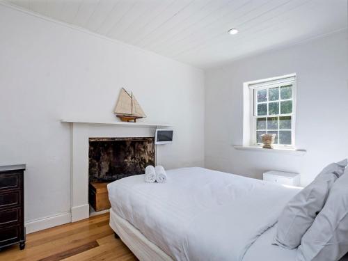 a white bedroom with a bed and a fireplace at Doran in Port Fairy